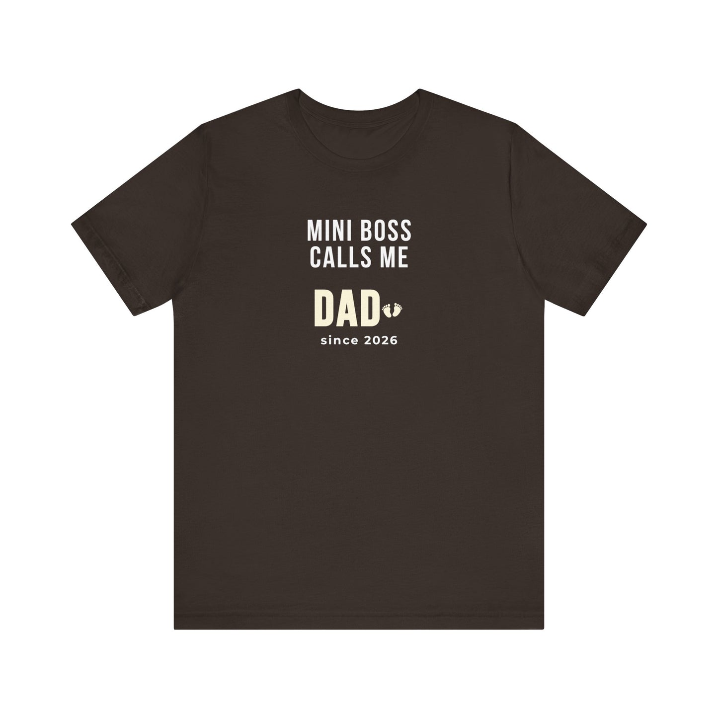 Brown t-shirt with white text 'Mini Boss Calls Me Dad – since 2026' on a white background