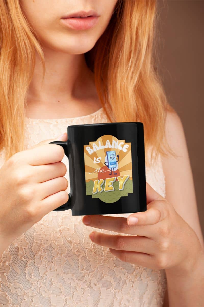 Balance is the Key Mug with a person holding a black mug with a colorful design and text.