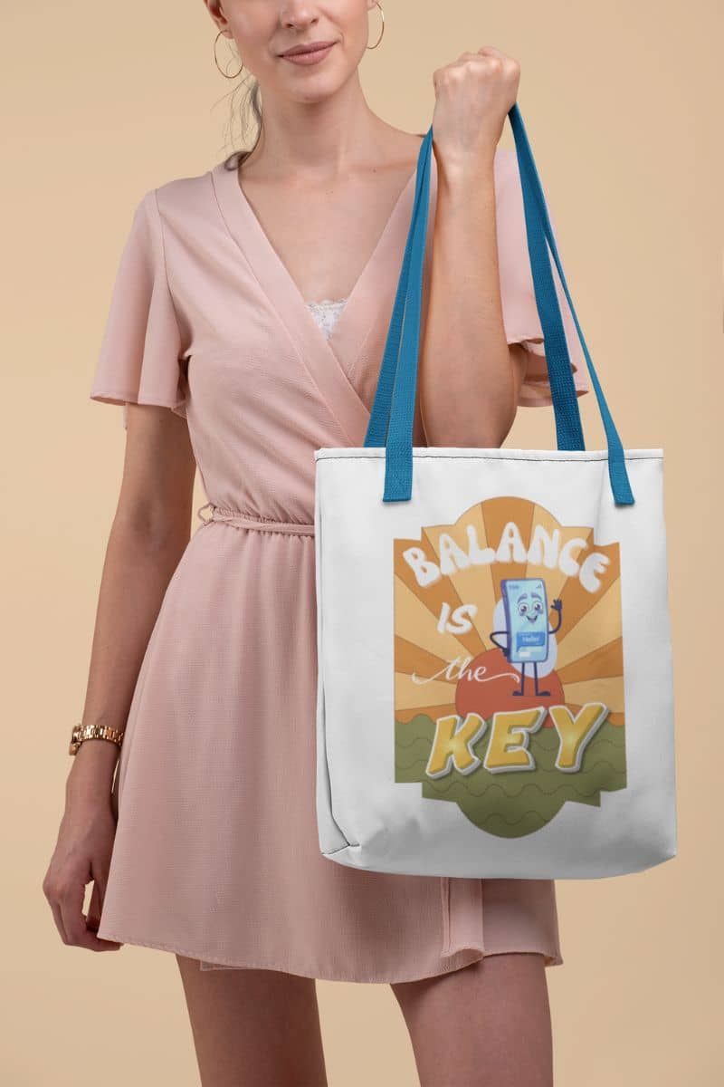 Balance is the Key Tote Bag with a woman holding a tote bag with 'Balance is the Key' design on a beige background