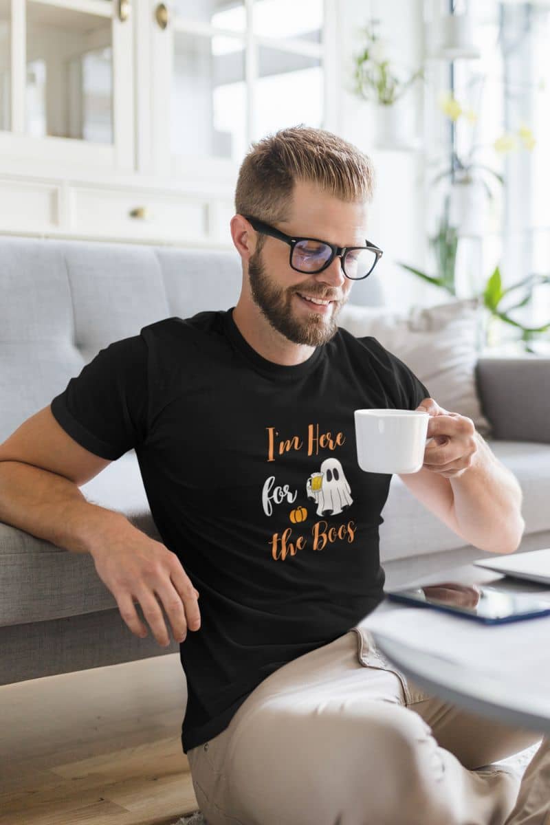 Boo crew shirt with a man in a black T-shirt that says “I’m Here for the Boos”, drinking tea.
