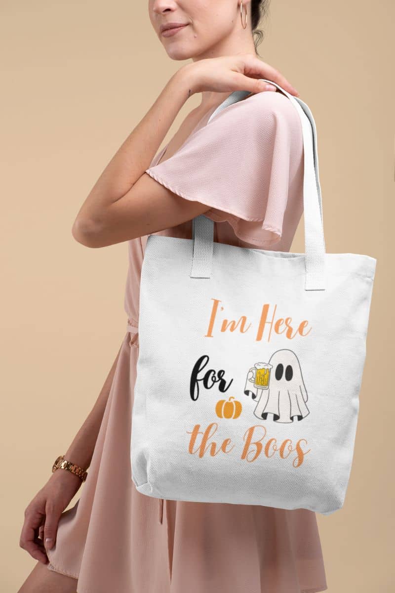 Boo crew tote bag with a person holding a tote bag with Halloween text and graphics on a beige background