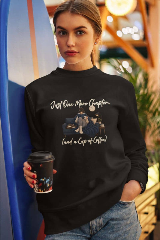 Book lover sweatshirt with a woman wearing a black crewneck sweatshirt featuring the text 'Just One More Chapter.'