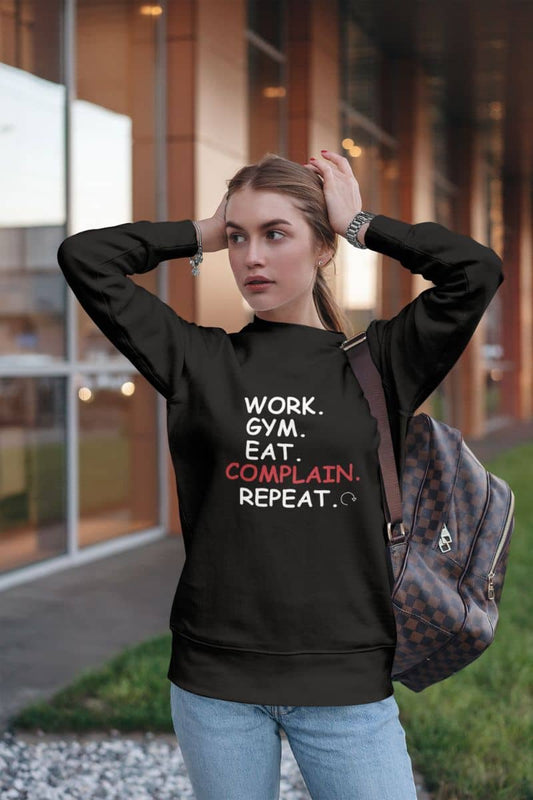 Casual pullover sweatshirt with a girl in a black hoodie with text 'Work. Gym. Eat. Complain. Repeat', standing outdoors.