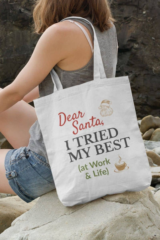 Christmas humor tote bag with  a person holding a tote bag with humorous text 'Dear Santa, I tried my best (at work & life)' on rocks