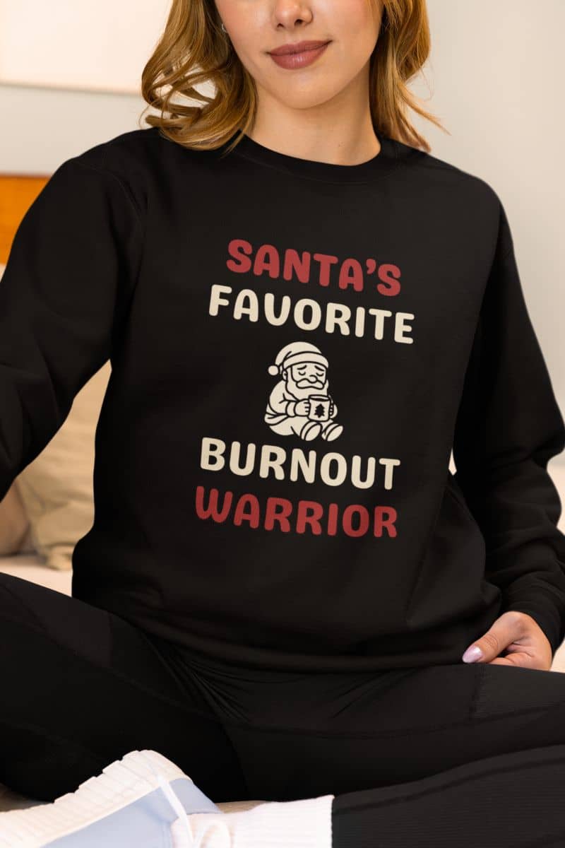 Christmas stress relief sweater with a person wearing a black sweatshirt with 'Santa's Favorite Burnout Warrior' text and graphic.