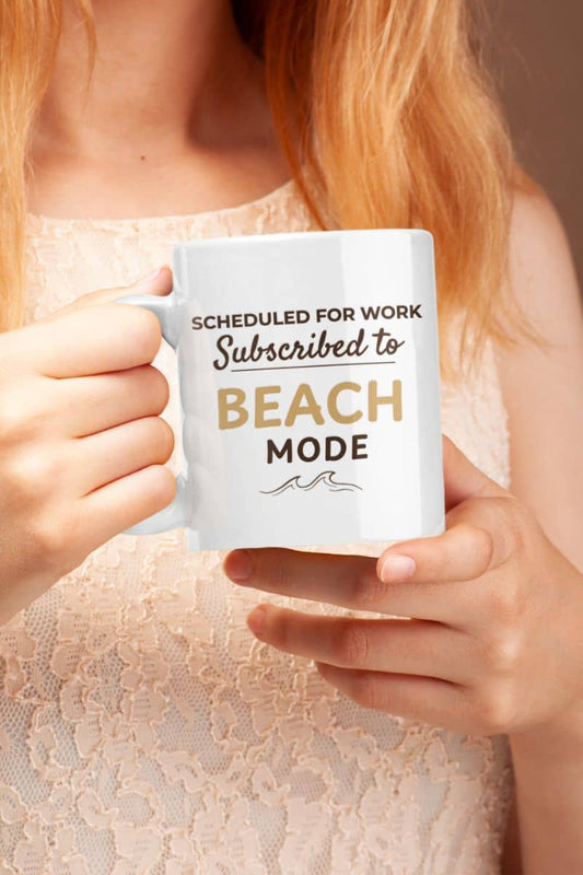 Coastal coffee mug with a person holding a mug with text 'Scheduled for work, Subscribed to Beach Mode'.