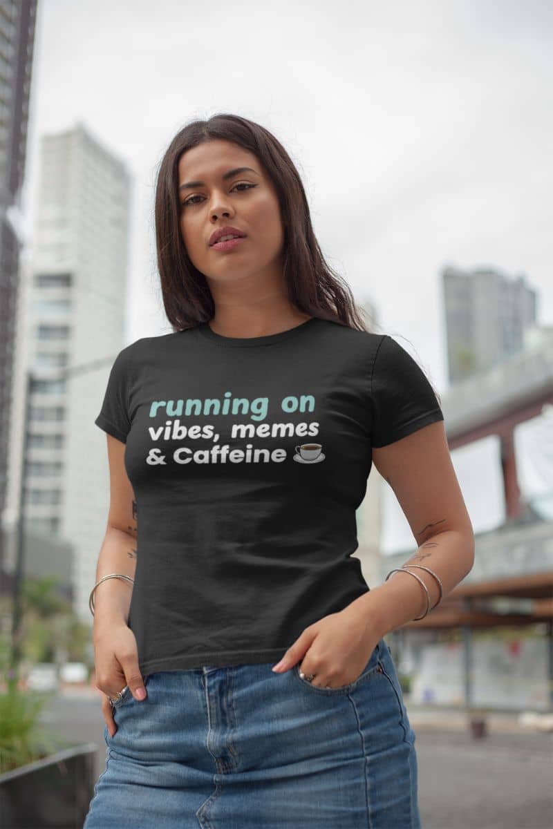 Coffee is my personality tee with a woman wearing a black t-shirt with text 'Running on Vibes, Memes & Caffeine'  in an urban setting
