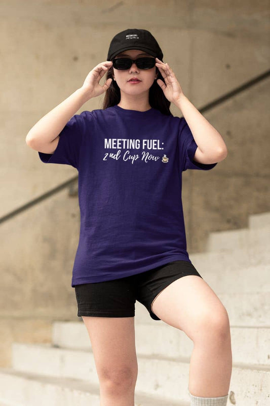 Coffee lovers shirt with a person in a purple t-shirt with text 'Meeting Fuel: 2nd Cup Now', wearing black cap, and sunglasses outdoors.