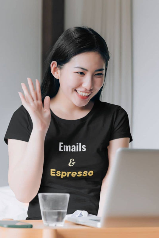 Coffee work t-shirt with a woman wearing a black t-shirt with 'Emails & Espresso' text, sitting at a desk with a laptop.