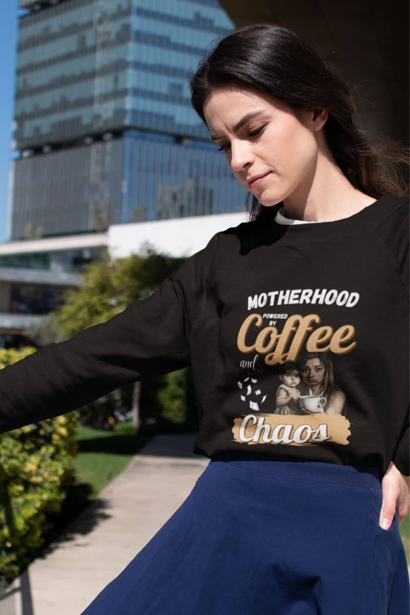 Comfy mom weatshirt with a girl leaning on the railing of the building and looking down at the ground