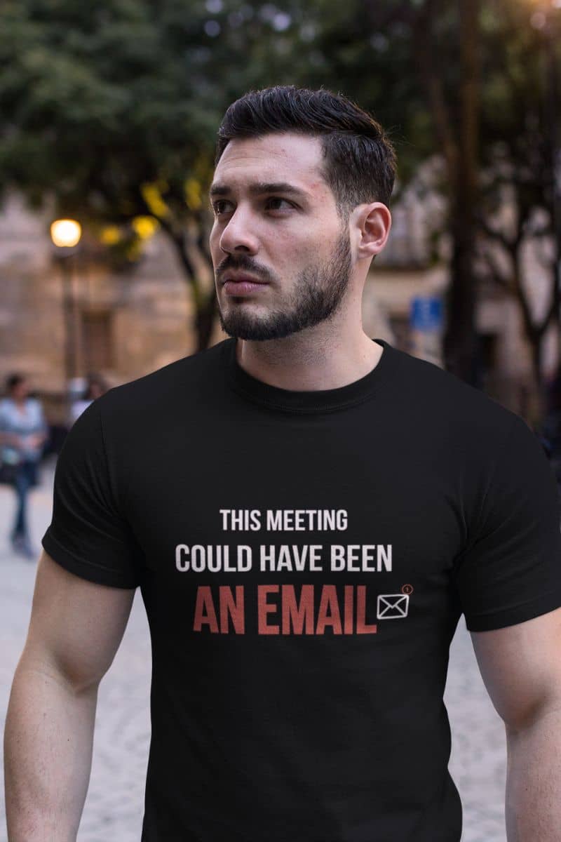 Corporate humor shirt with a man wearing a black t-shirt with text 'This Meeting Could Have Been An Email' in an urban setting 