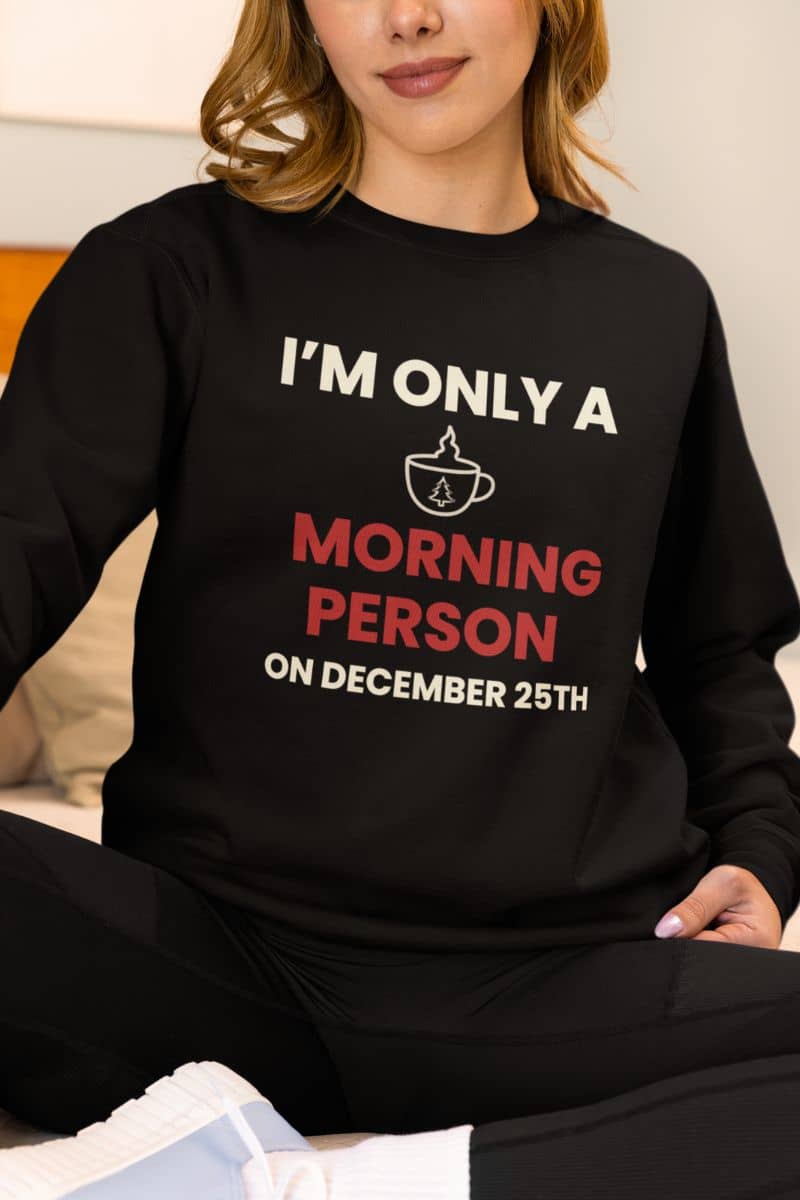Cozy christmas coffee sweater with a person wearing a black sweatshirt with humorous text 'I’m Only a Morning Person on December 25th'