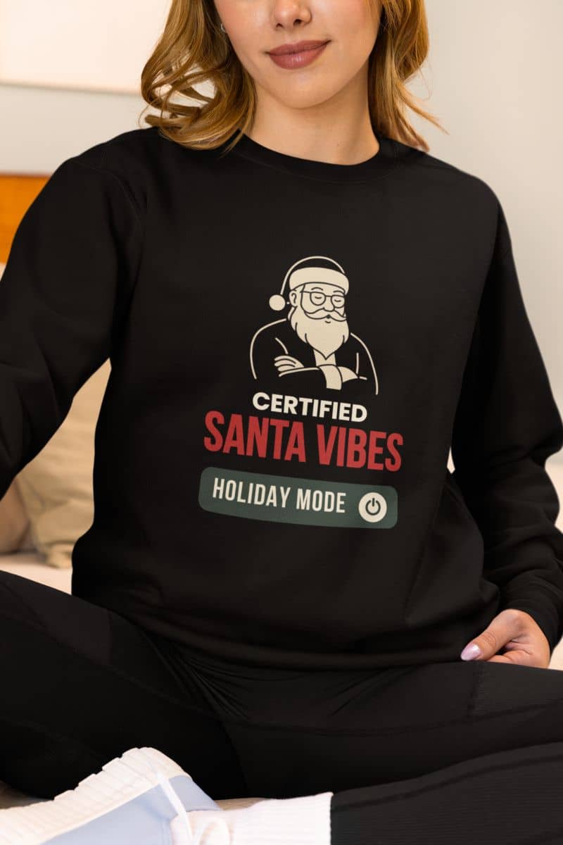 Cozy holiday sweatshirt for adults with a person wearing a black sweatshirt with a graphic and text 'Certified Santa Vibes Holiday Mode'.