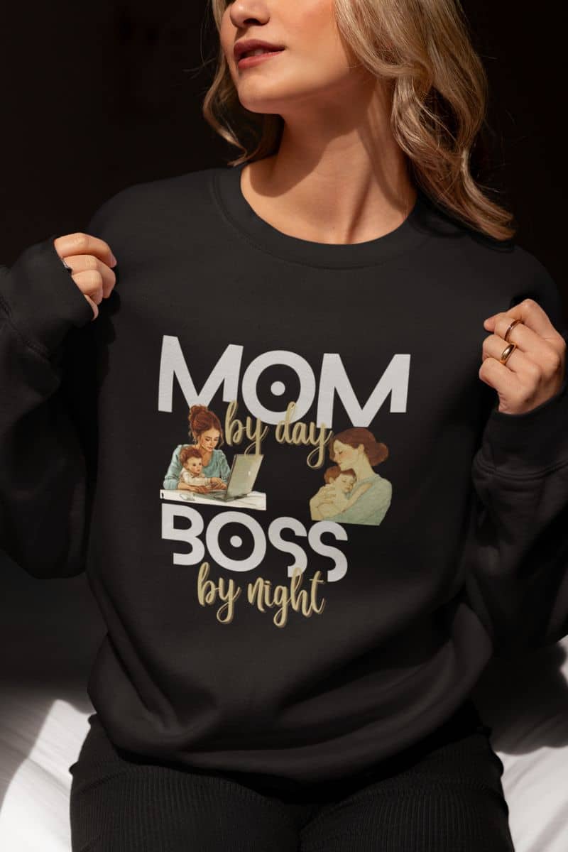 Cozy sweatshirt for moms with a woman wearing a black sweatshirt featuring the text 'Mom by day, Boss by night' and graphics