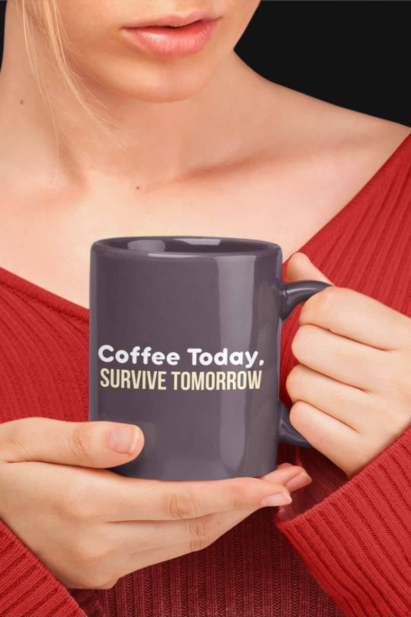Daily grind ceramic mug with a person holding a mug with 'Coffee Today. Survive Tomorrow' text