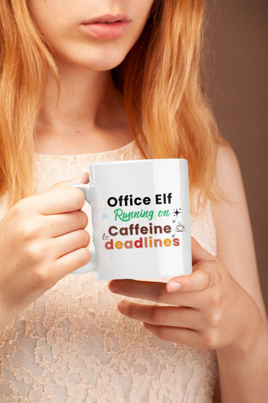 Deadline survival mug with a person holding a mug with text 'Office Elf Running on Caffeine & Deadlines' against a neutral background