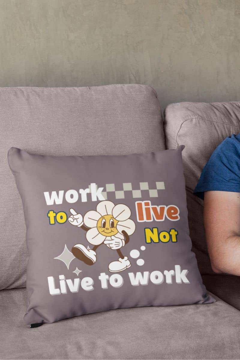 Decorative quote pillow with a square pillow placed on the sofa next to a man working on a laptop