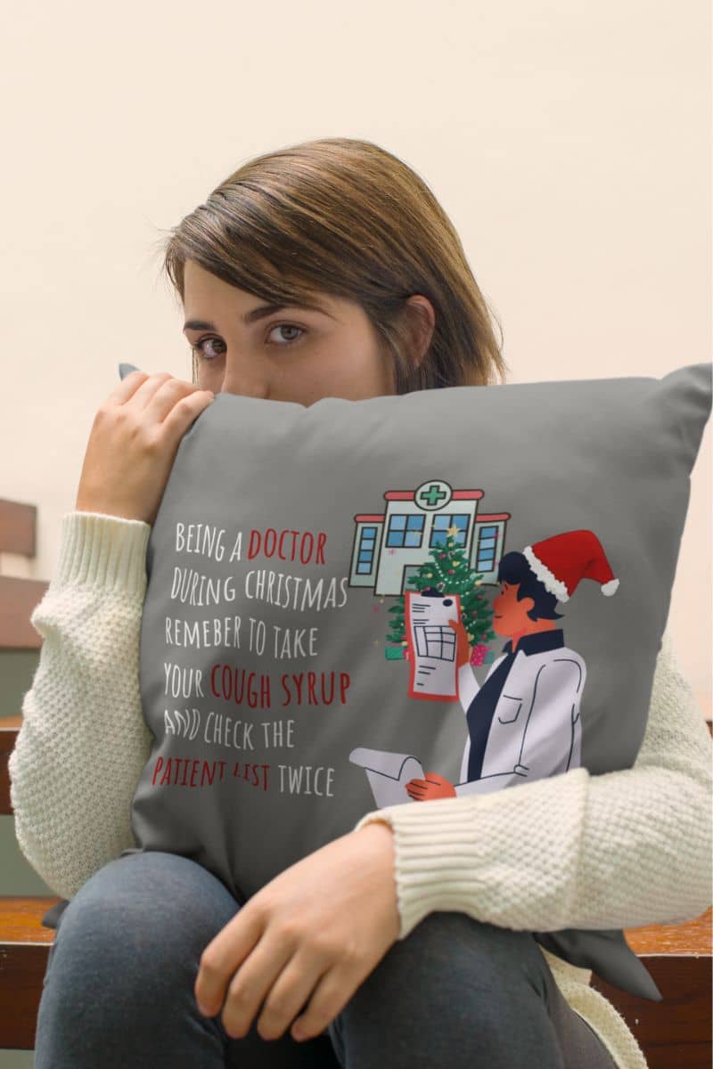 Doctor's christmas humor pillow with a girl hugging a pillow covering half her face on a wooden chair
