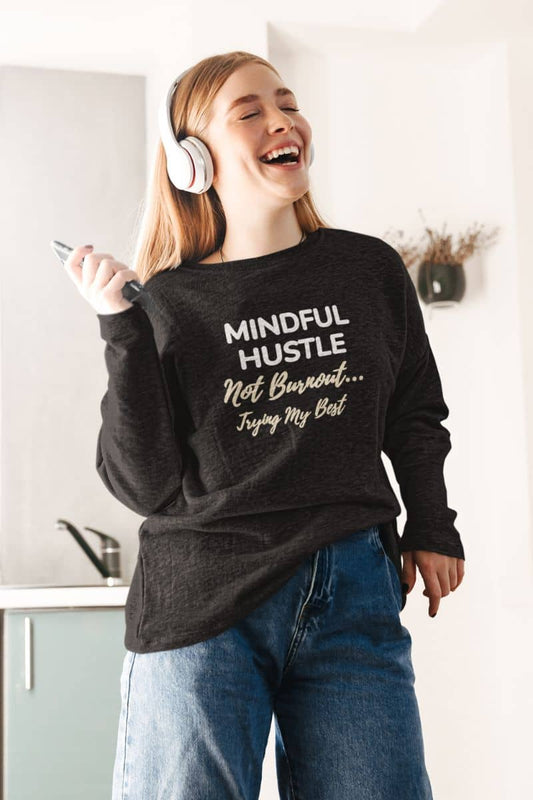 Doing my best sweatshirt with a person wearing a black sweatshirt with text 'Mindful Hustle – Not Burnout… Trying My Best', holding a phone, and smiling.