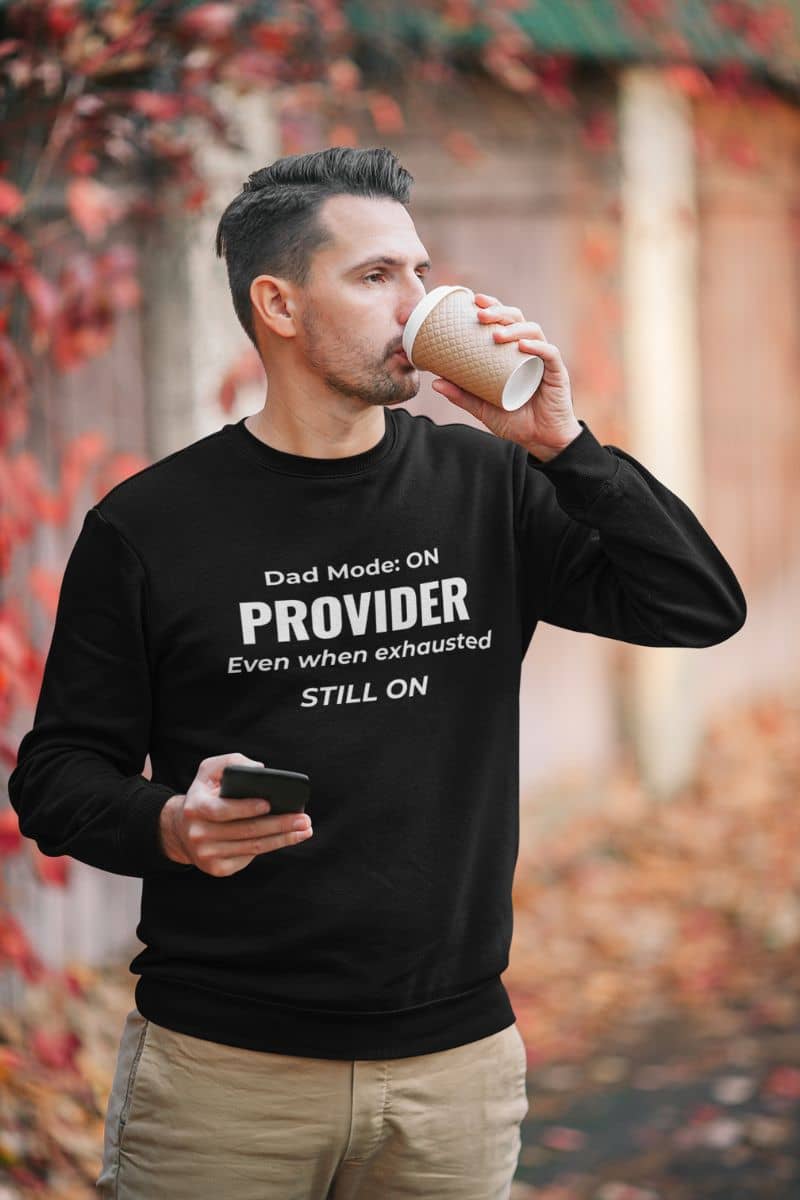Emotional dad sweatshirt with a man wearing a sweatshirt featuring the text 'Dad Mode: On. Provider. Even when exhausted. Still on'