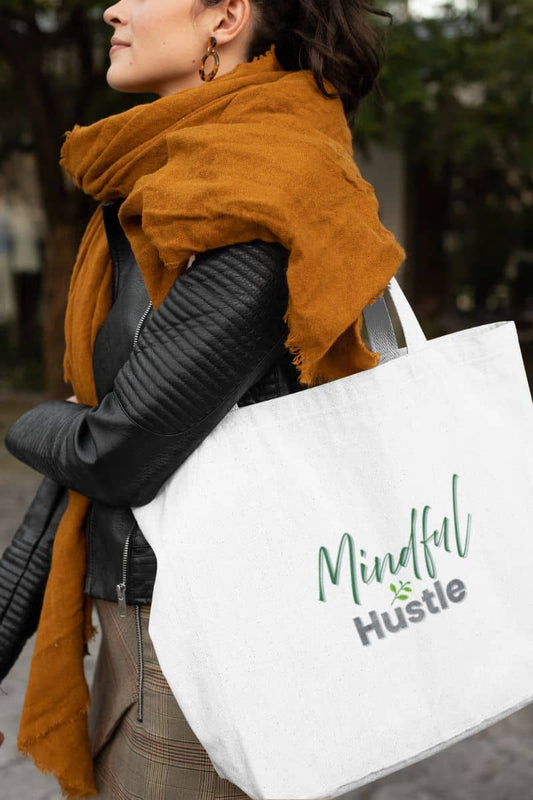 Empowering tote bag for women with a person holding a white tote bag with 'Mindful Hustle' branding outdoors.