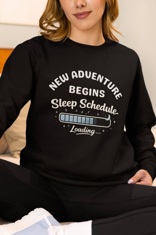 Exhausted life sweatshirt with a person wearing a black sweatshirt with text 'New adventure begins sleep schedule loading'.
