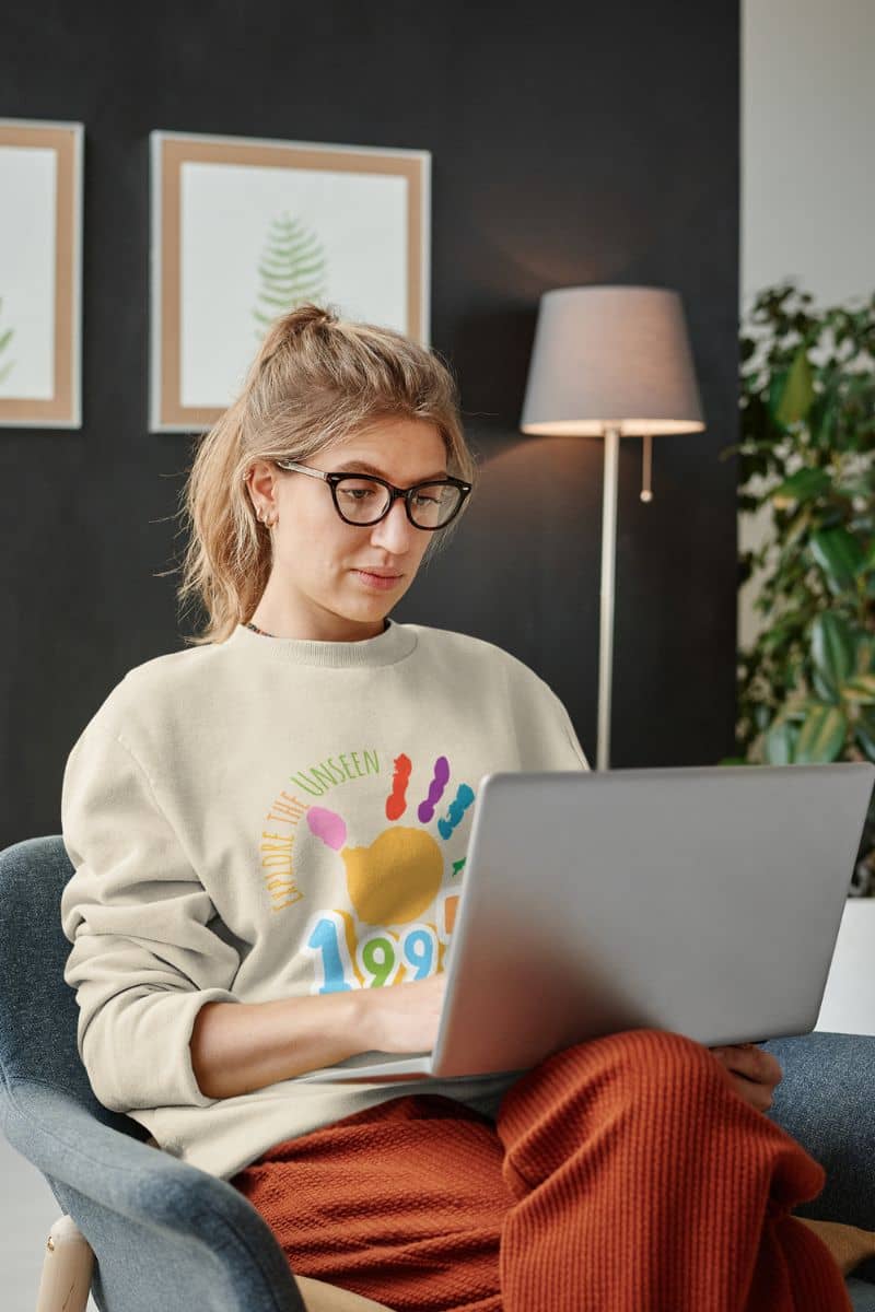 Explore the Unseen Sweatshirt with girl sitting working with laptop on sofa
