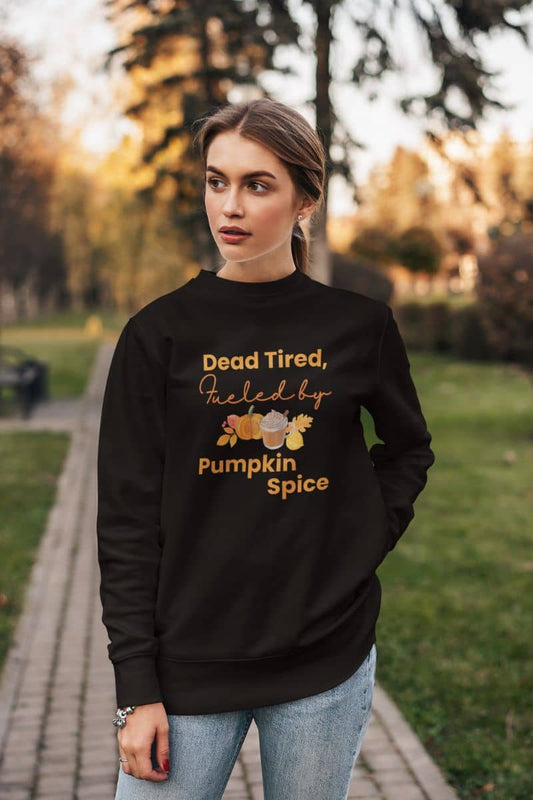 Fall coffee sweatshirt with a woman wearing a black sweatshirt with text 'Dead Tired, Fueled by Pumpkin Spice' in an outdoor setting