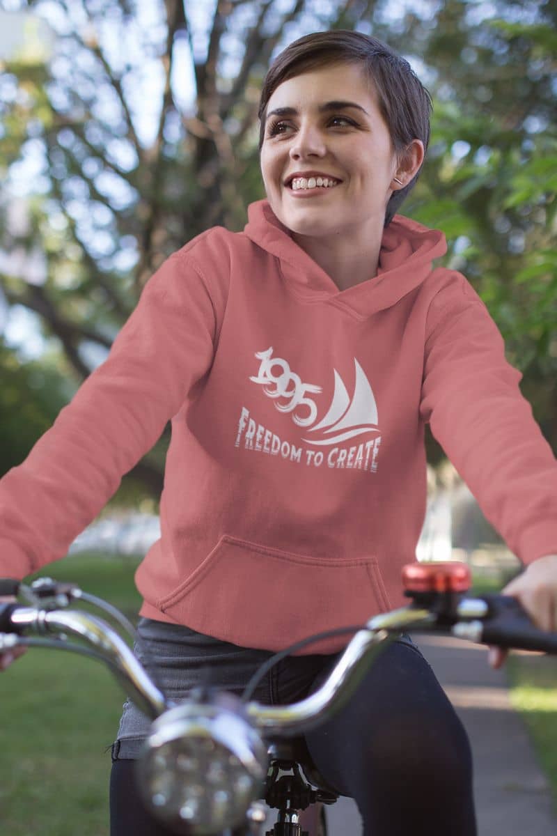 Freedom to Create Unisex Hooded Sweatshirt with a girl riding a bike with a bright smile