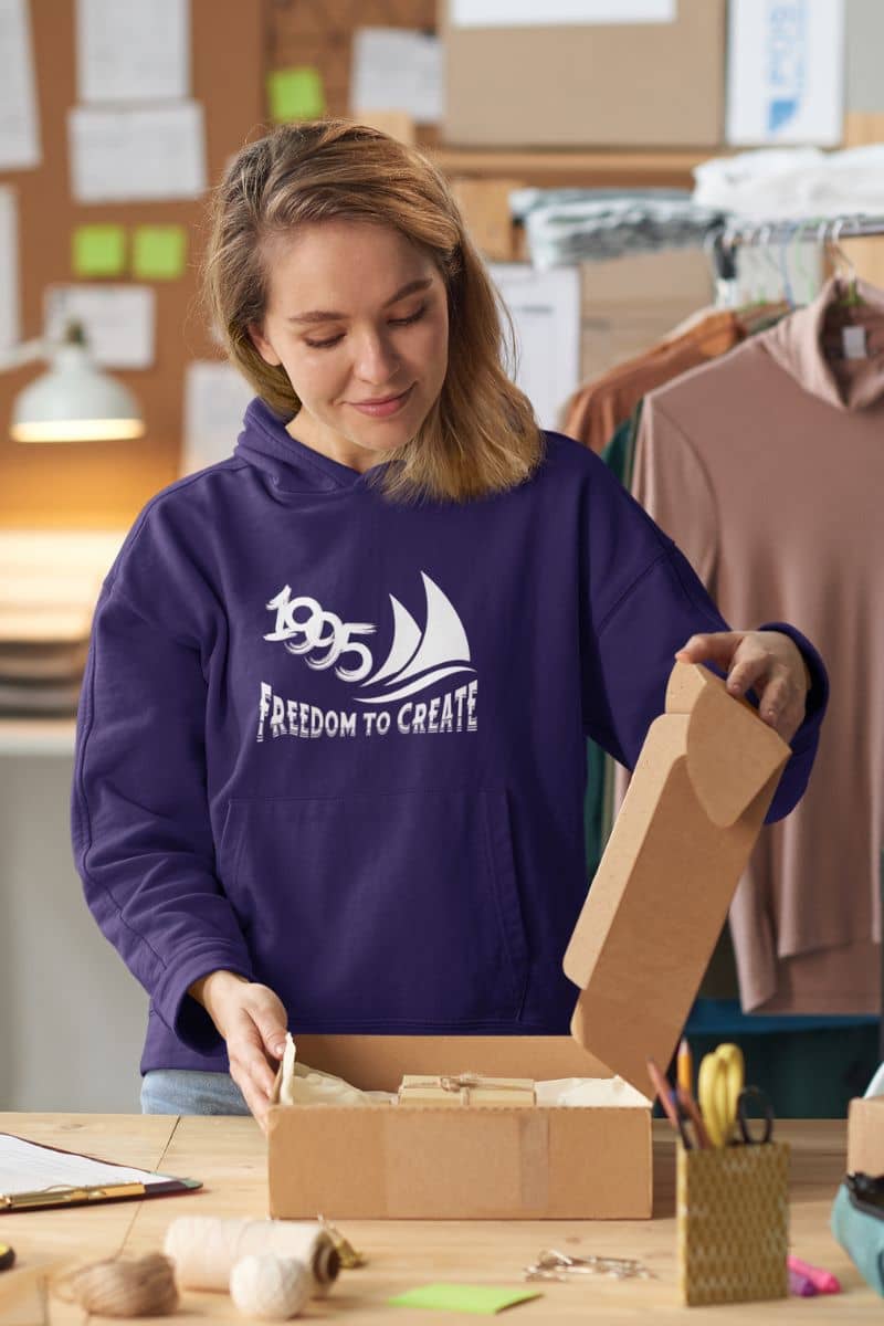 Freedom to Create Unisex Hooded Sweatshirt with a girl packing products in her store