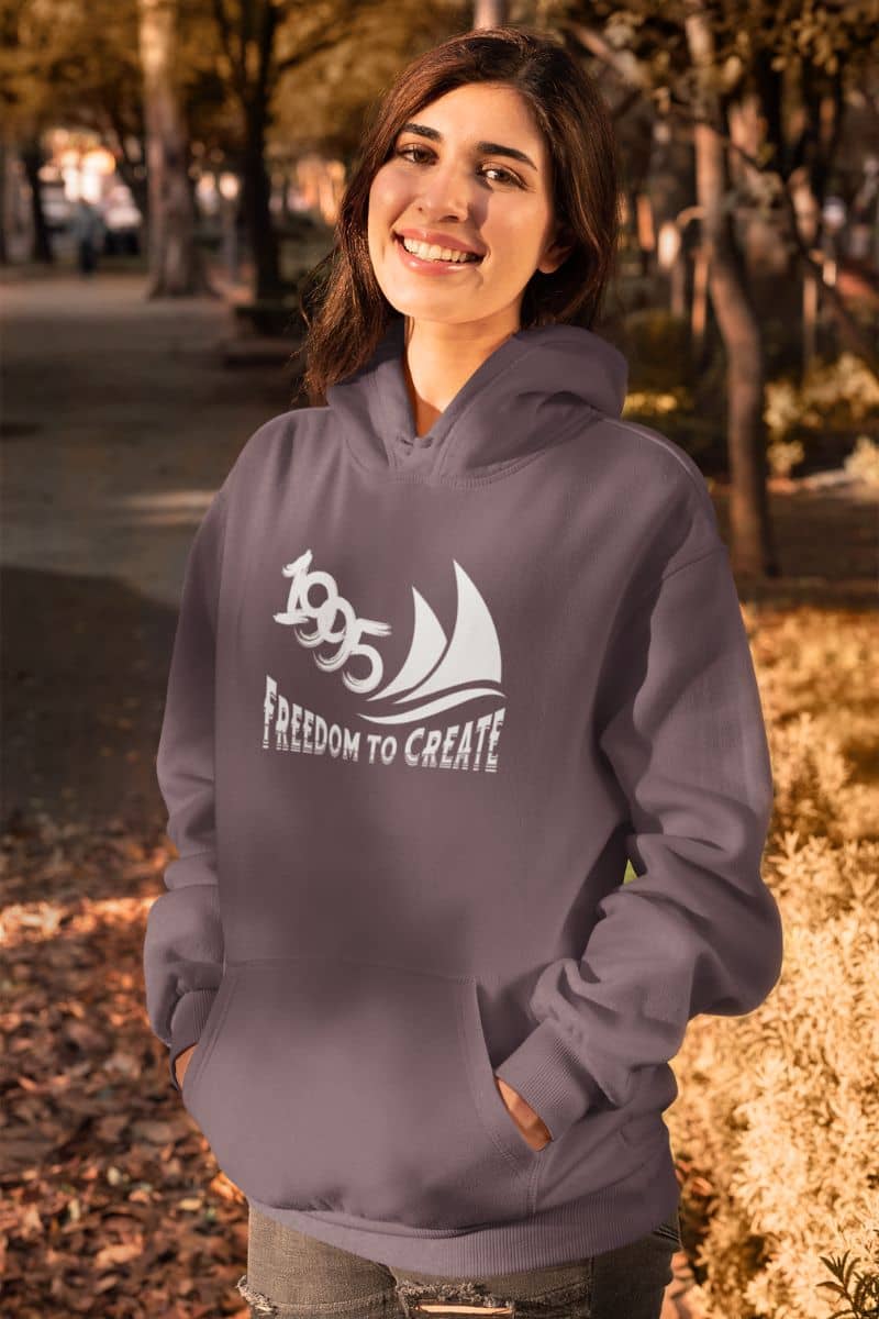 Freedom to Create Unisex Hooded Sweatshirt with a girl posing with a bright smile and hands in her pockets