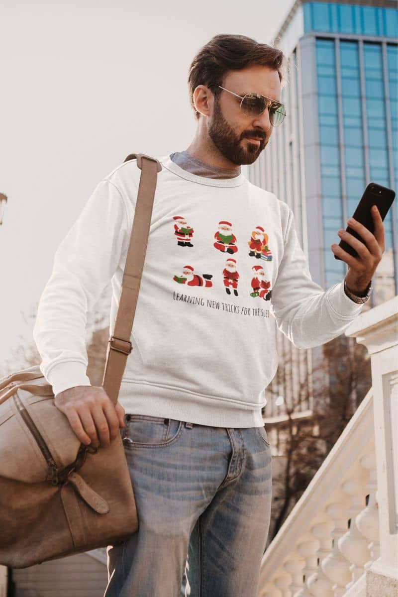 Learning New Stricks For The Sleigh - Fun Christmas Sweatshirt with a guy carrying a bag and looking at his phone