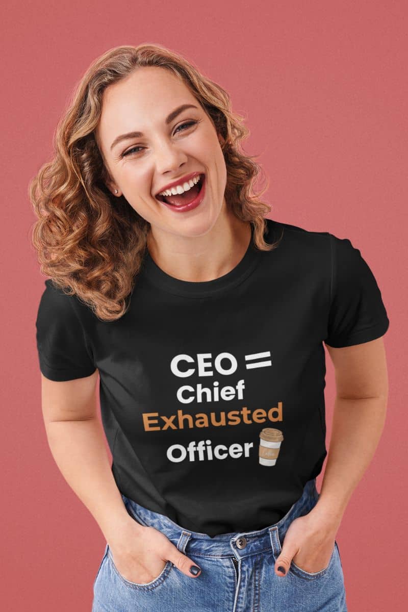 Funny CEO t-shirt with a woman wearing a black t-shirt with a humorous office quote 'CEO = Chief Exhausted Officer' on a pink background