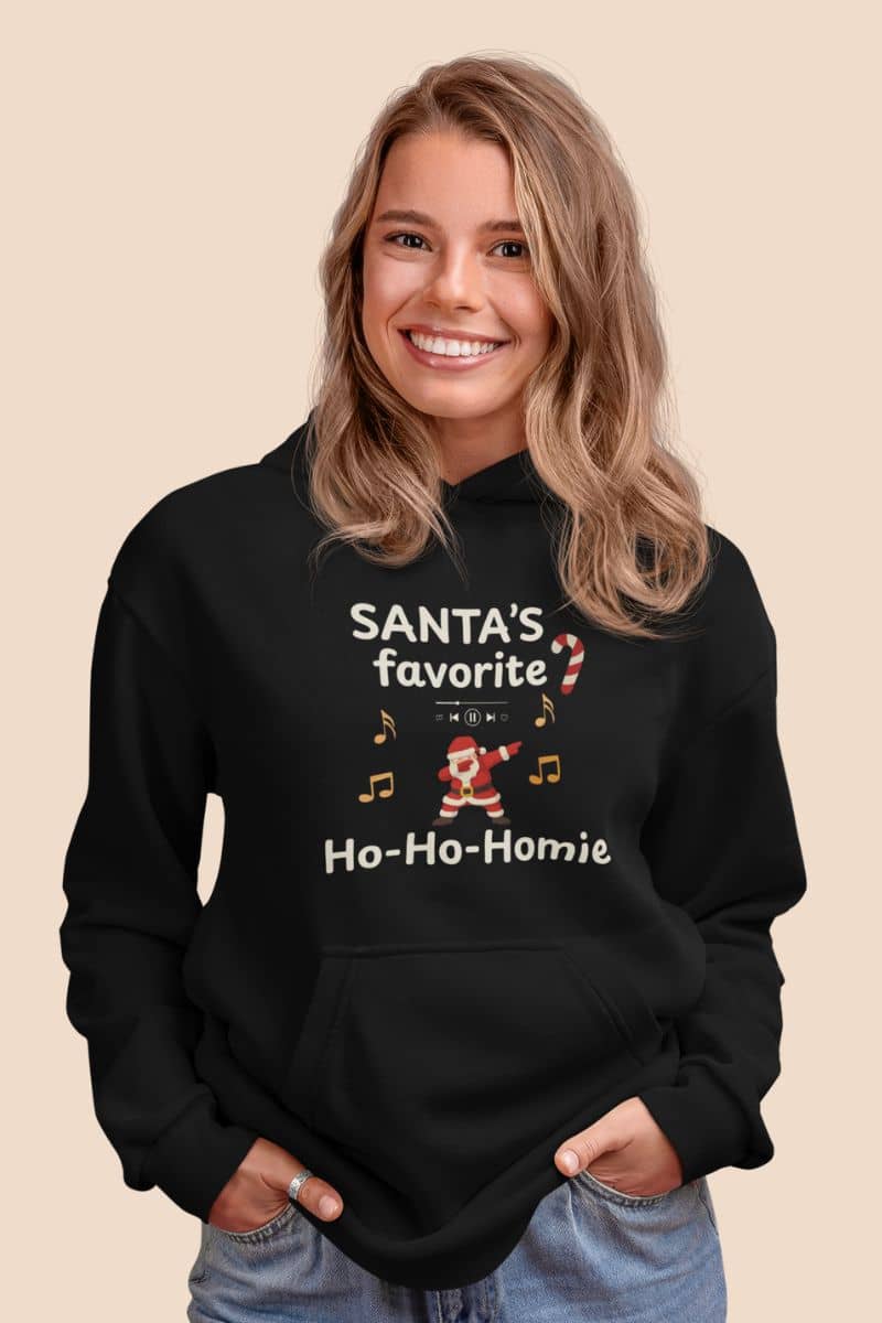 Funny Santa Christmas hoodie with a person wearing a black hoodie with text 'Santa's Favorite Ho-Ho-Homie' and graphics on a beige background