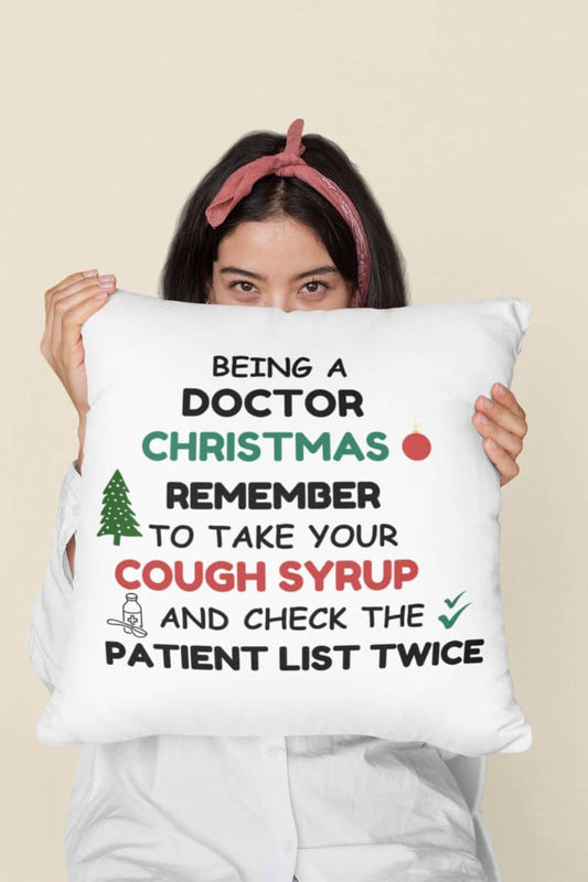 Funny doctor christmas pillow with a person holding a pillow with text 'Being a doctor during Christmas, remember to take your cough syrup and check the patient list twice'.