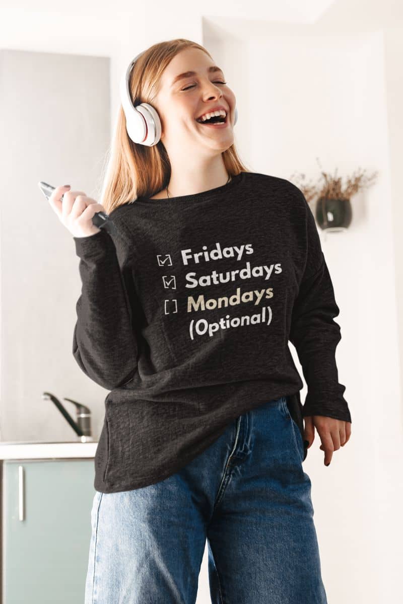 Funny monday sweatshirt with a person wearing a black sweatshirt with text 'Fridays and Saturdays, Mondays (Optional)', standing in a kitchen.