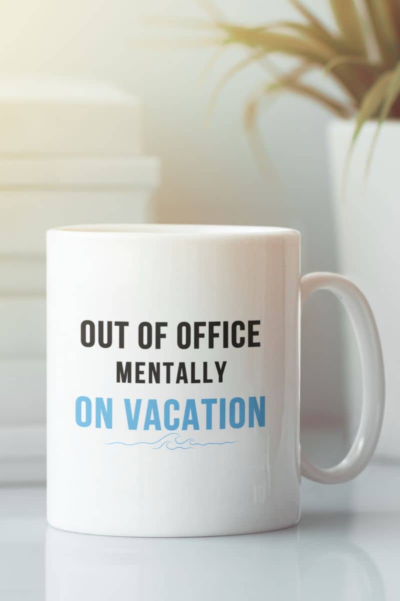 Funny office mug with a white mug with text 'Out of Office Mentally On Vacation' on a blurred background