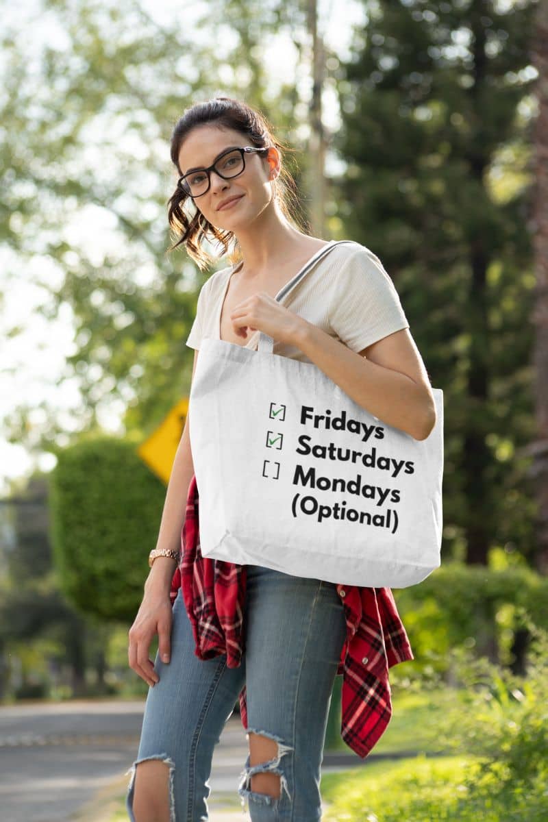 Funny tote bag with a woman holding a tote bag with text 'Fridays and Saturdays, Mondays (Optional)' outdoors