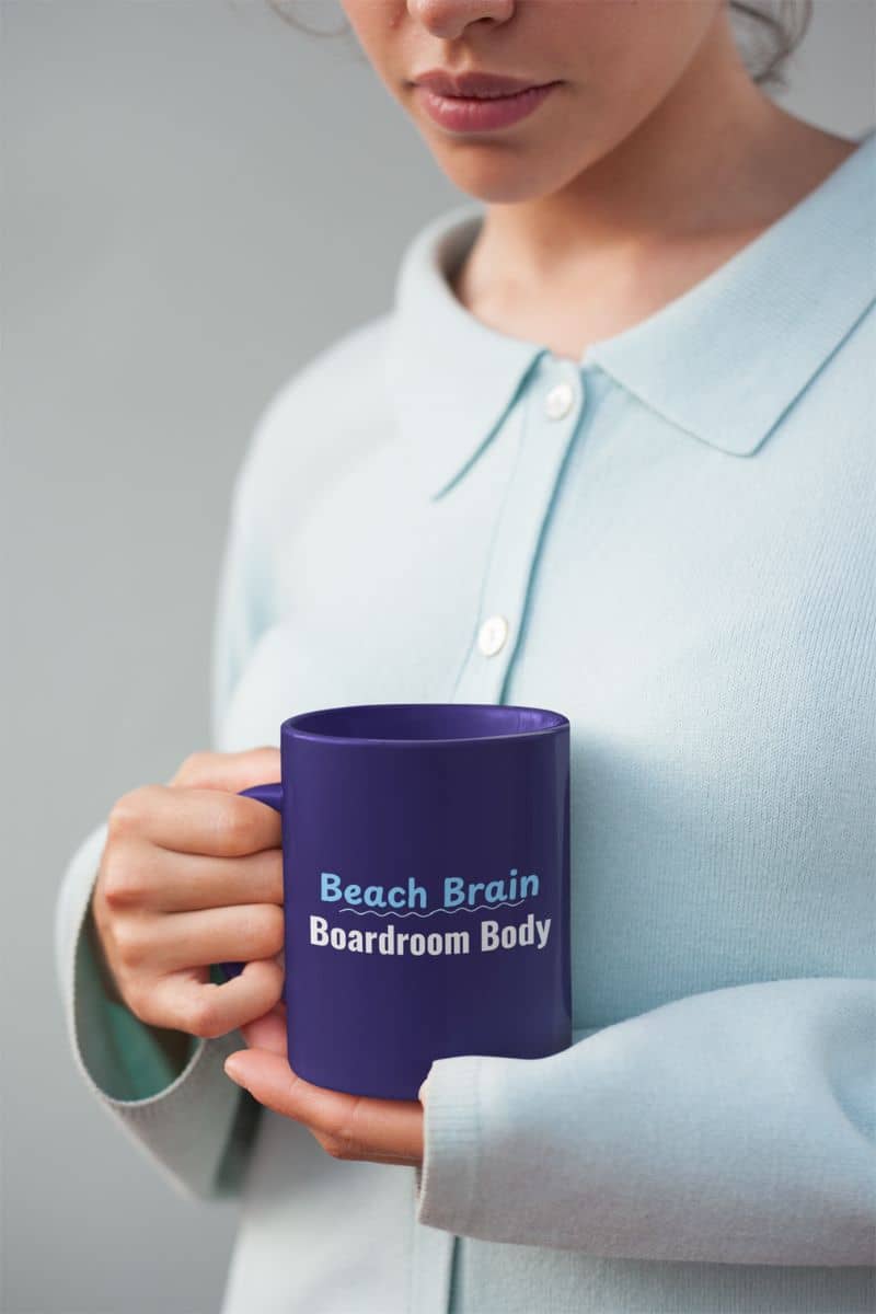 Funny travel coffee mug with a person holding a blue mug with 'Beach Brain Boardroom Body' text against a neutral background