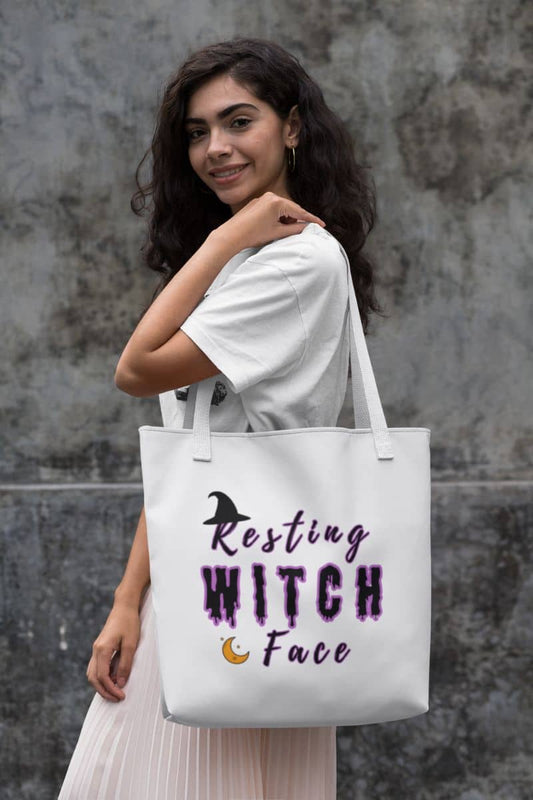 Funny witch tote with  a woman holding a tote bag with 'Resting Witch Face' text against a gray wall.