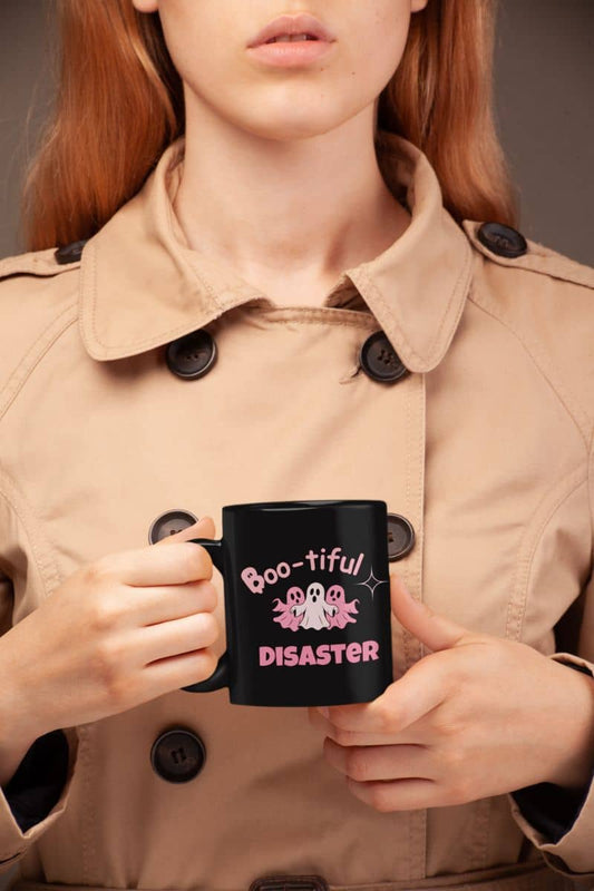Halloween coffee mug with a person holding a black mug with 'Boo-tiful Disaster' text, wearing a beige trench coat.