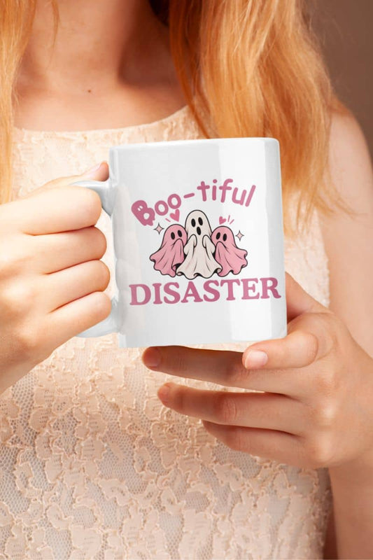 A woman holding a Halloween coffee mug featuring the text 'Boo-tiful Disaster' with three ghosts