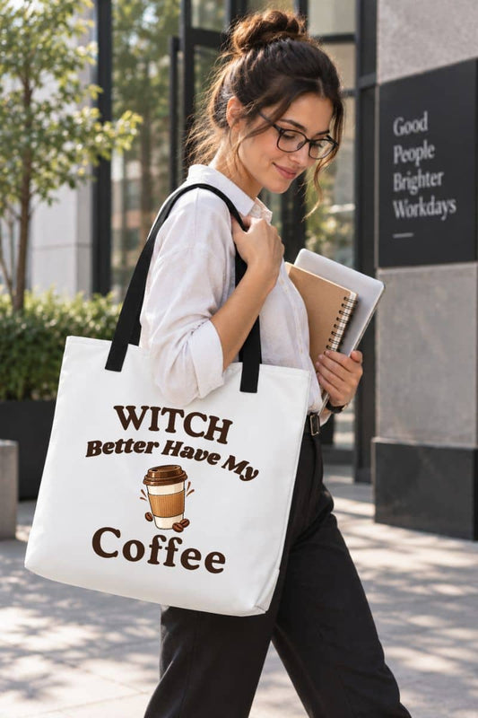 Halloween coffee tote bag with a woman walking outdoors carrying a white canvas tote bag with black handles and the printed phrase 'Witch Better Have My Coffee' along with a coffee cup graphic.