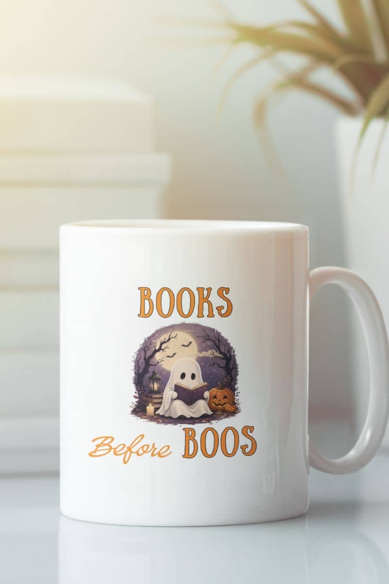 Halloween mug with a white mug featuring the text 'Books Before Boos', placed on the table