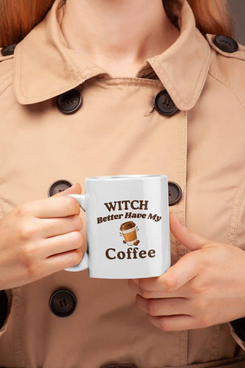 Halloween mug with a person holding a white ceramic mug with the printed text 'Witch Better Have My Coffee' 