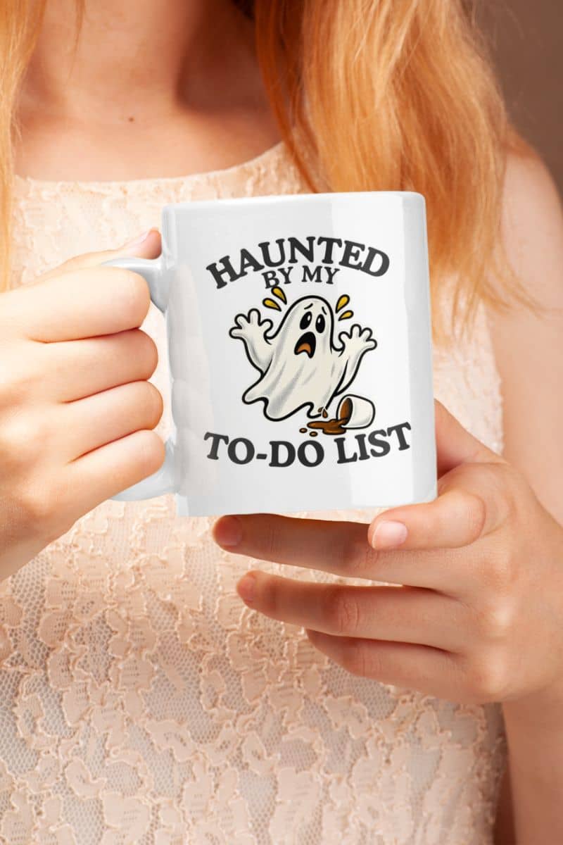 A person holding a Halloween themed mug featuring a “Haunted by My To-Do List” funny ghost