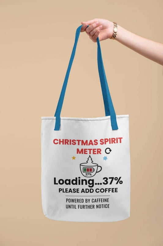 Holiday coffee tote bag with a tote bag featuring the text 'Christmas Spirit Meter, Loading…37%. Please add coffee. Powered by caffeine until further notice' on a beige background