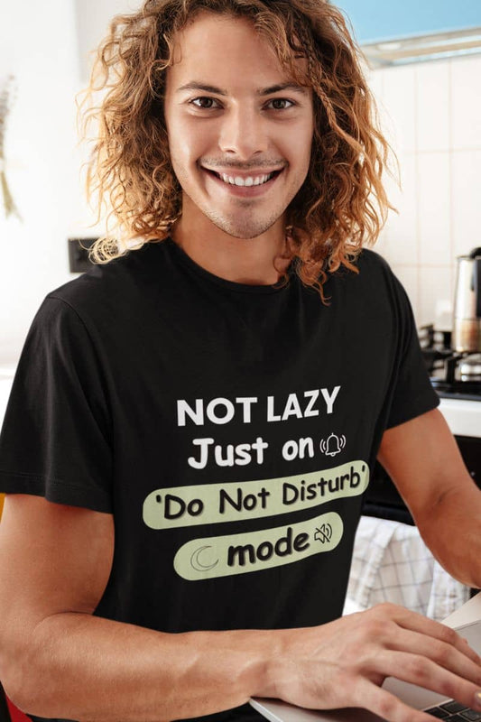 Introvert mode t-shirt with a person wearing a black t-shirt with humorous text 'NOT LAZY, Just on 'Do Not Disturb' mode' in a kitchen setting