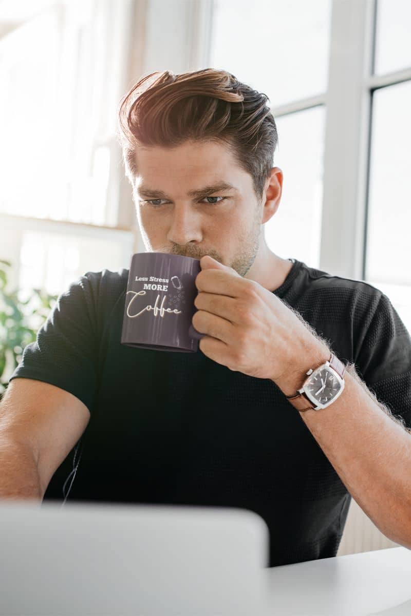 Less stress more coffee mug with a guy drinking water and working on his laptop