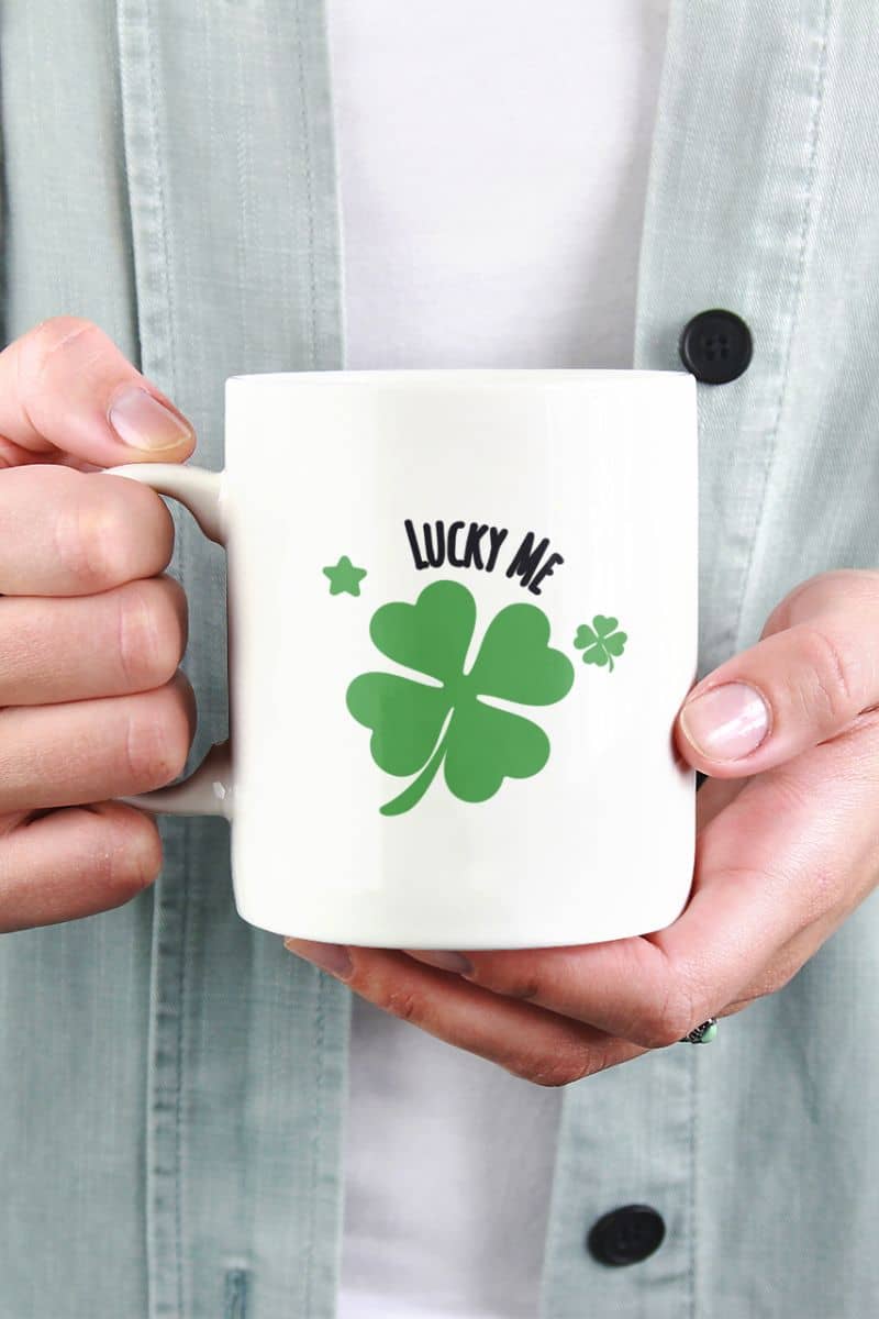 Lucky symbol coffee mug with a person holding a mug with a green four-leaf clover and 'Lucky Me' text.